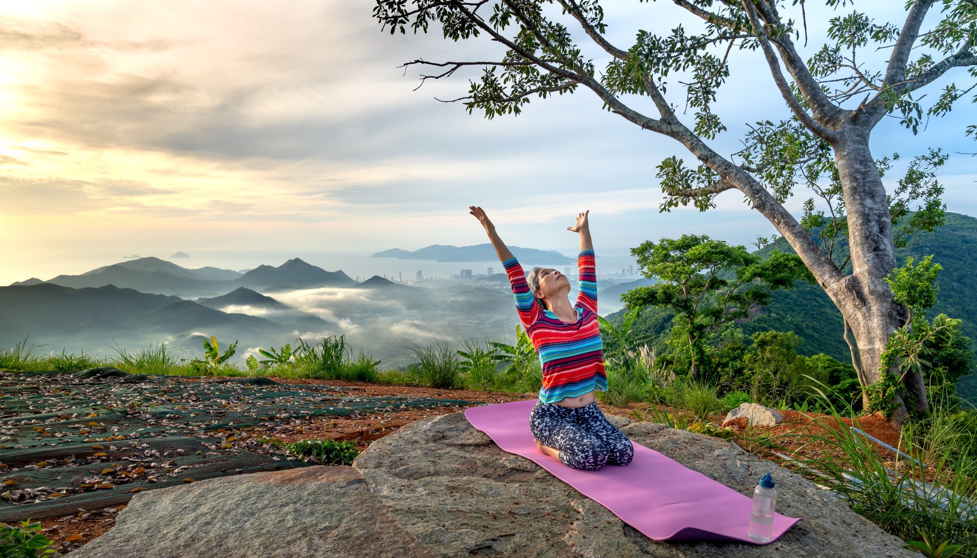 A guest breathing in the sunrise on a hilltop, arms open to the mountain view